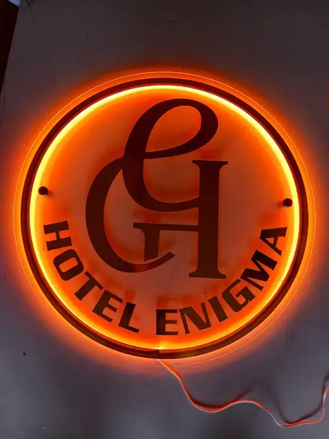 Warm backlit circular logo sign fabricated for Hotel Enigma