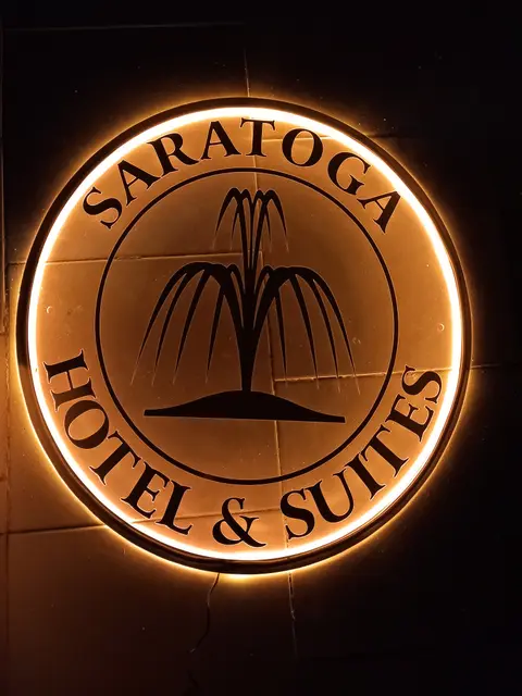 Warm backlit circular fountain logo for Saratoga Hotel and Suites