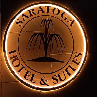 Warm backlit circular fountain logo for Saratoga Hotel and Suites