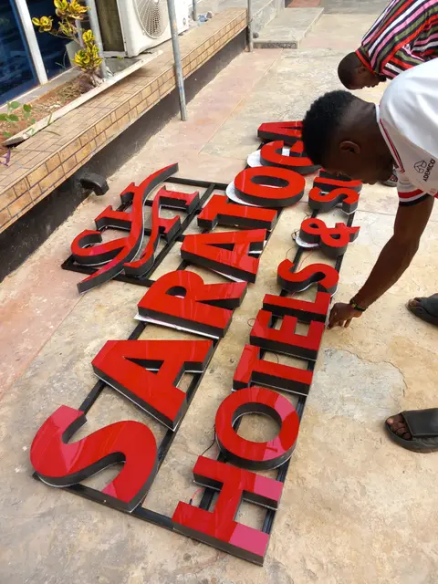 Fabricator checking the red Saratoga channel letters laid out before install
