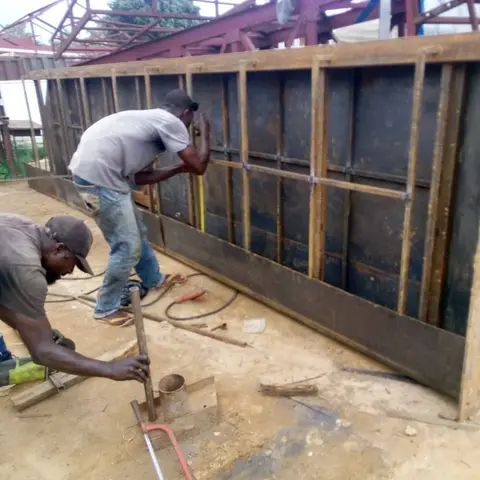 Two PRECISION fabricators building a large steel sign structure in the workshop